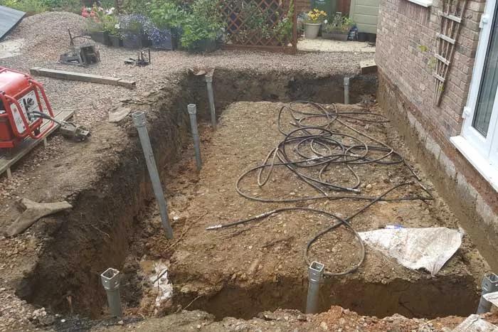 Excavated foundations alongside a house